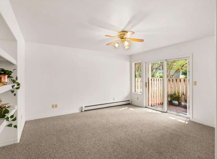 Step into this inviting living space featuring a cozy carpeted floor and a convenient ceiling fan for year-round comfort.