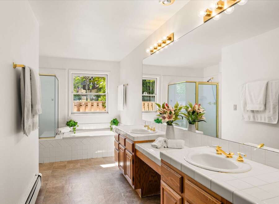This spacious bathroom features a large soaking tub with a window overlooking the backyard, perfect for relaxation.