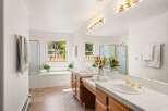 This spacious bathroom features a large soaking tub with a window overlooking the backyard, perfect for relaxation.