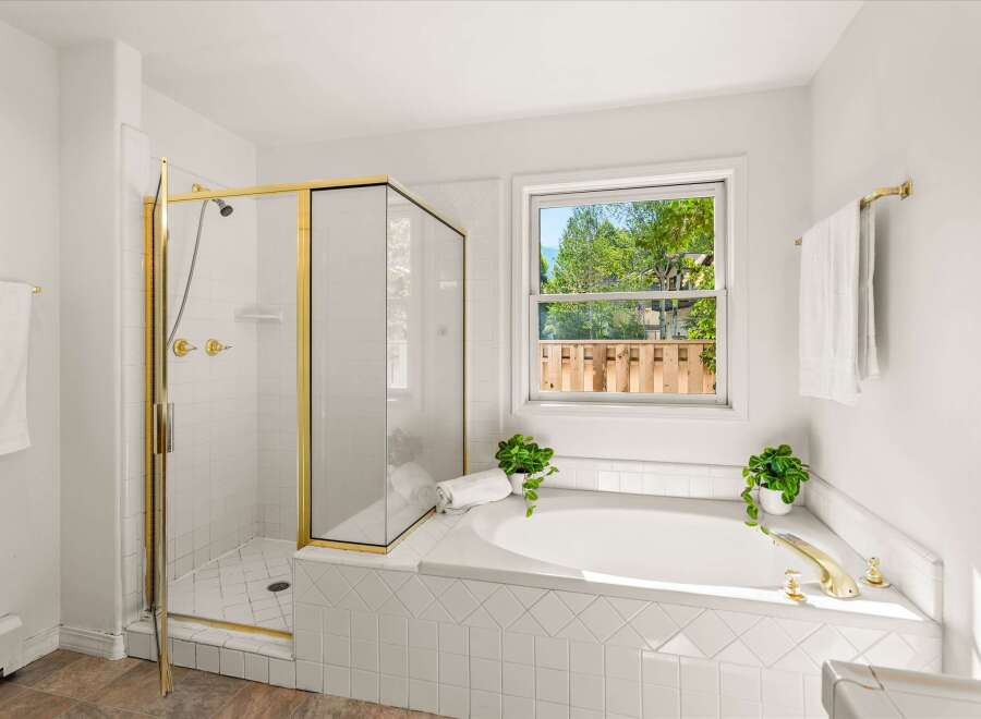 Indulge in relaxation in this luxurious bathroom featuring a spacious corner bathtub with elegant gold fixtures.