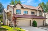 This charming townhouse features a light beige exterior with a durable, dark red metal roof.