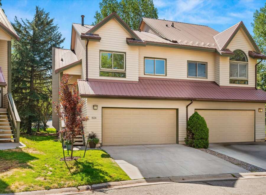 Discover this charming townhome featuring a light beige exterior with a contrasting dark red metal roof.
