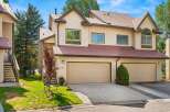 Discover this charming townhome featuring a light beige exterior with a contrasting dark red metal roof.