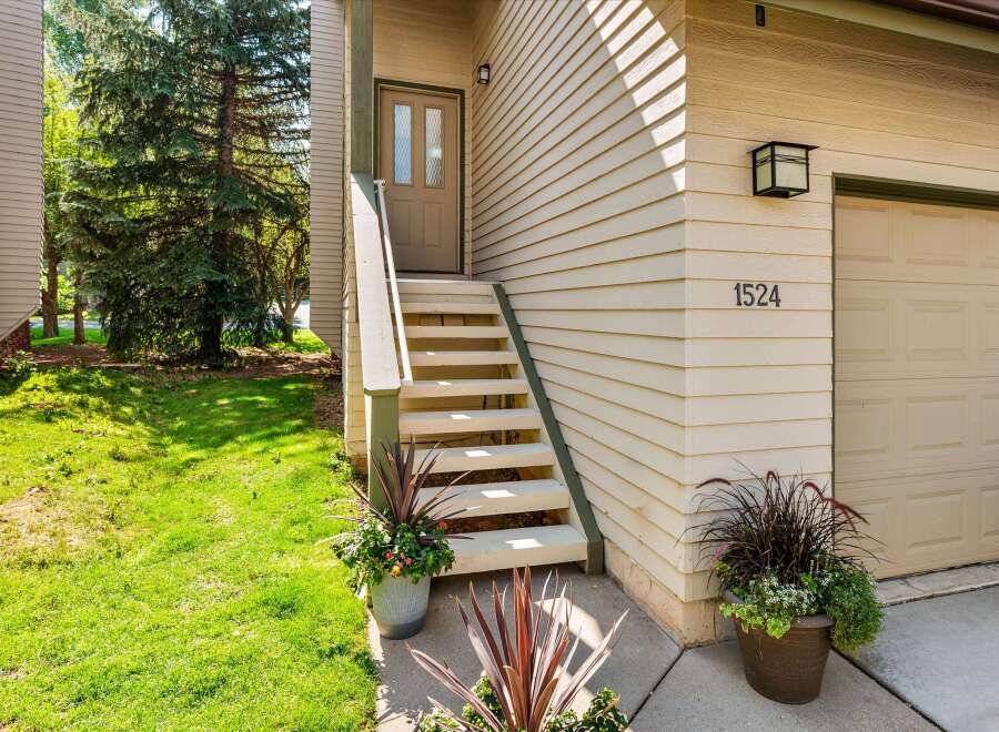 Welcome to this charming home featuring a welcoming front entrance with a light beige door and two glass panes, leading up a set of stairs.