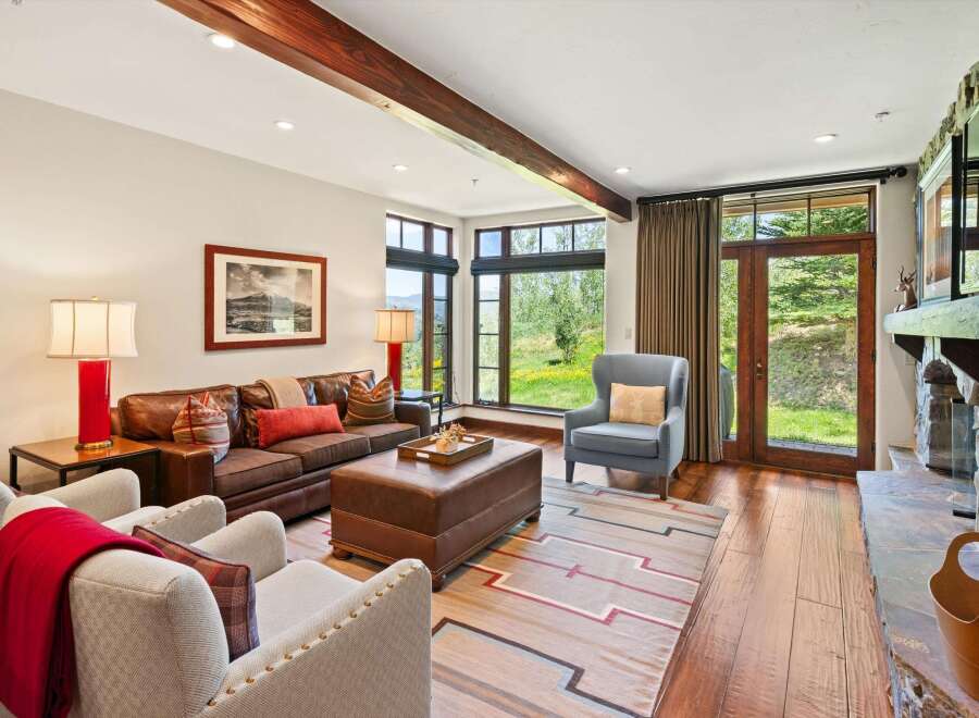 Experience rustic elegance in this inviting living room, featuring a rich leather sofa complemented by plush accent chairs and a large leather ottoman.