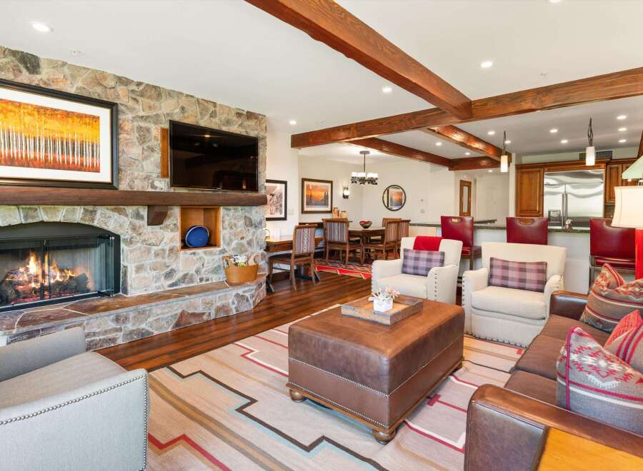 Experience rustic elegance in this inviting living space, featuring a grand stone fireplace and exposed wooden beams that create a warm, cozy atmosphere.