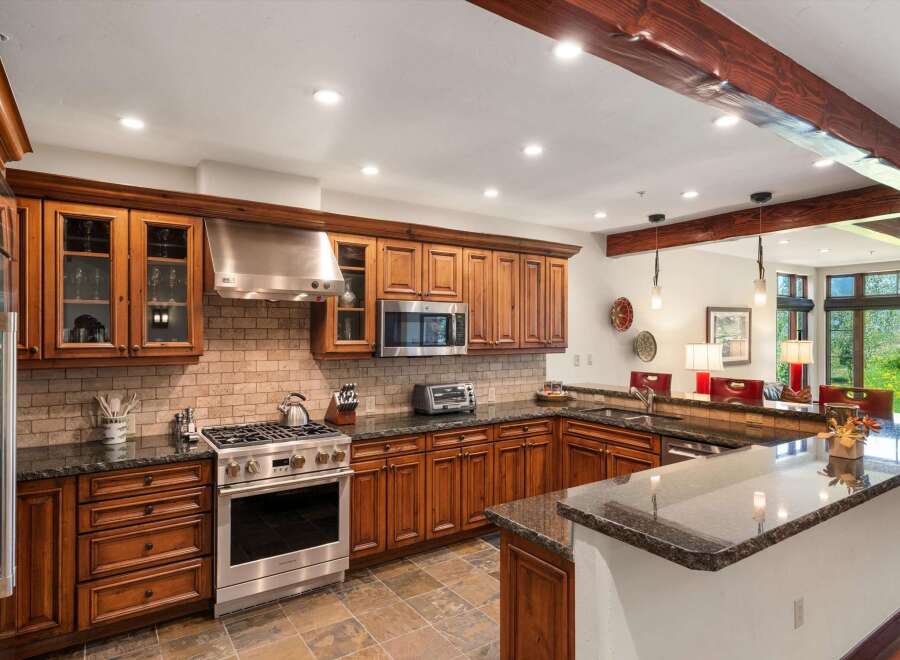 Experience luxury mountain living in this stunning kitchen, featuring rich cherry wood cabinetry, granite countertops, and a professional-grade stainless steel range.