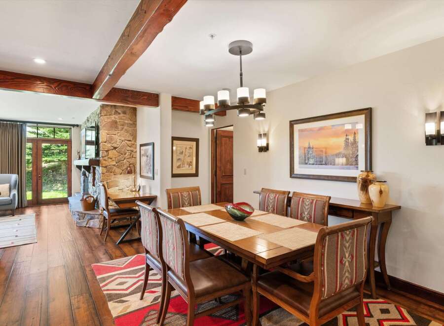 Experience rustic elegance in this dining room, featuring a substantial wooden dining table set for six, complemented by chairs upholstered in a Native American-inspired fabric.
