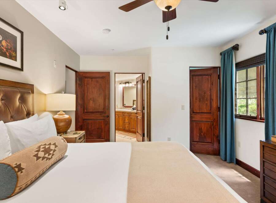 Experience rustic charm in this inviting bedroom, featuring a luxurious leather headboard and a cozy bolster pillow with a Native American-inspired pattern.