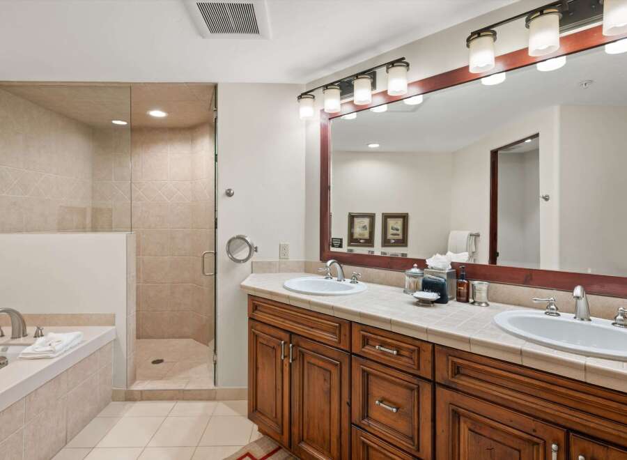 Indulge in luxury with this spacious bathroom featuring a deep soaking tub and a separate glass-enclosed shower with elegant tilework.