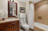 This charming bathroom features a spacious vanity with a granite countertop and a deep basin sink, complemented by a large wooden-framed mirror.