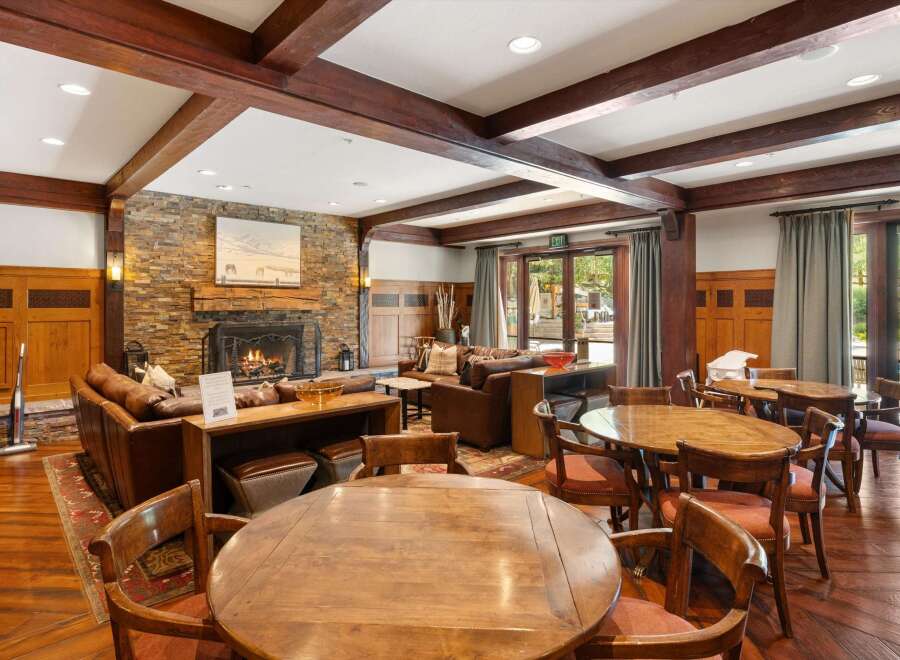 Experience rustic elegance in this inviting lodge-style living area, featuring a grand stone fireplace and exposed wooden beams.
