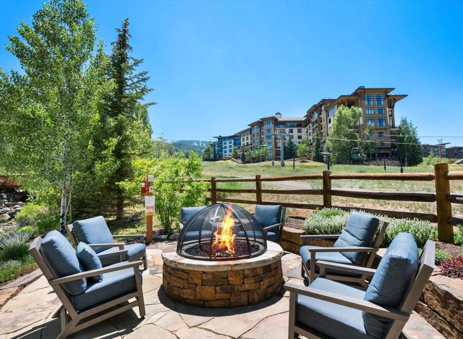 Enjoy breathtaking mountain views from this luxurious outdoor living space, complete with a stone fire pit and comfortable seating.