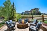 Enjoy breathtaking mountain views from this luxurious outdoor living space, complete with a stone fire pit and comfortable seating.