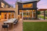 Experience luxurious outdoor living with this stunning modern home, featuring a spacious dining area set on a gravel patio, perfect for al fresco entertaining.