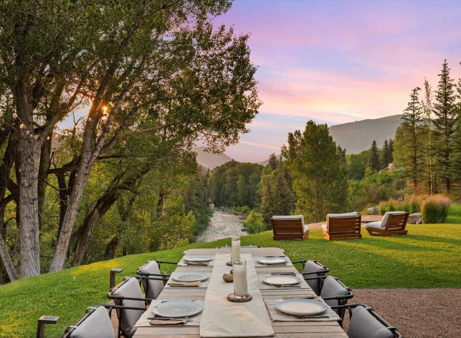 Experience luxurious outdoor dining with a stunning mountain backdrop and a serene river view.