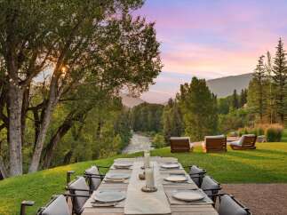Experience luxurious outdoor dining with a stunning mountain backdrop and a serene river view.