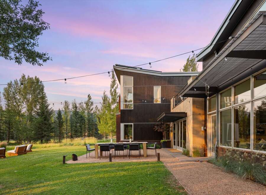 Experience modern luxury in this stunning property featuring a sleek, dark wood exterior and expansive glass windows.