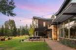 Experience modern luxury in this stunning property featuring a sleek, dark wood exterior and expansive glass windows.
