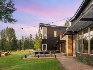 Experience modern luxury in this stunning property featuring a sleek, dark wood exterior and expansive glass windows.