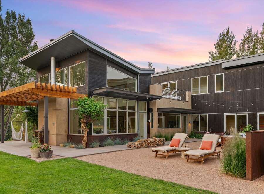 Experience modern luxury in this stunning home featuring dark wood siding and expansive windows that invite natural light.