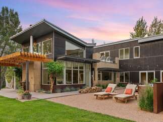 Experience modern luxury in this stunning home featuring dark wood siding and expansive windows that invite natural light.