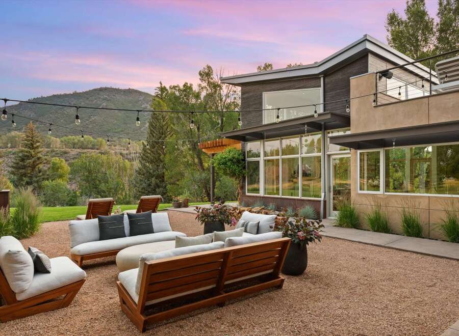Experience luxurious outdoor living with this stunning patio featuring modern wooden furniture and plush cushions, perfect for relaxing or entertaining.