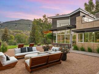 Experience luxurious outdoor living with this stunning patio featuring modern wooden furniture and plush cushions, perfect for relaxing or entertaining.