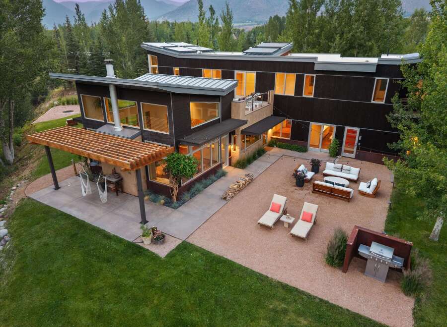 Experience modern luxury in this stunning contemporary home, featuring sleek dark wood siding and expansive windows that invite natural light.