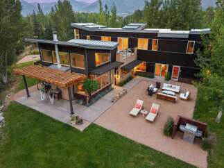 Experience modern luxury in this stunning contemporary home, featuring sleek dark wood siding and expansive windows that invite natural light.