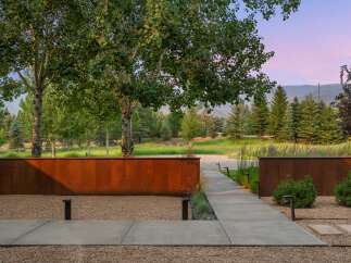 Experience modern luxury with this stunning property featuring a sleek concrete pathway leading through a serene landscape.