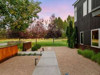 Experience modern luxury with this stunning property featuring a dark wood exterior and expansive windows that capture the serene landscape.