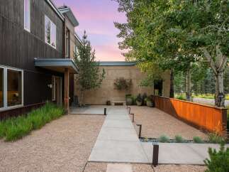 Experience modern luxury with this stunning property featuring dark wood siding and expansive windows that capture the beautiful twilight sky.