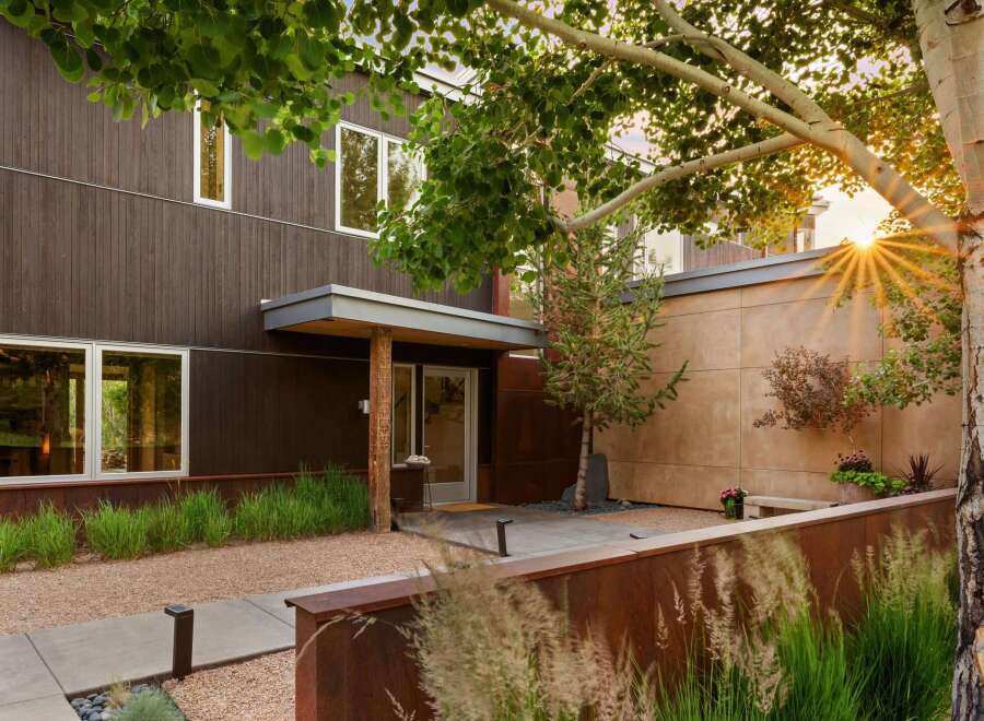 Experience modern living in this stunning home featuring dark wood siding and expansive windows that invite natural light.