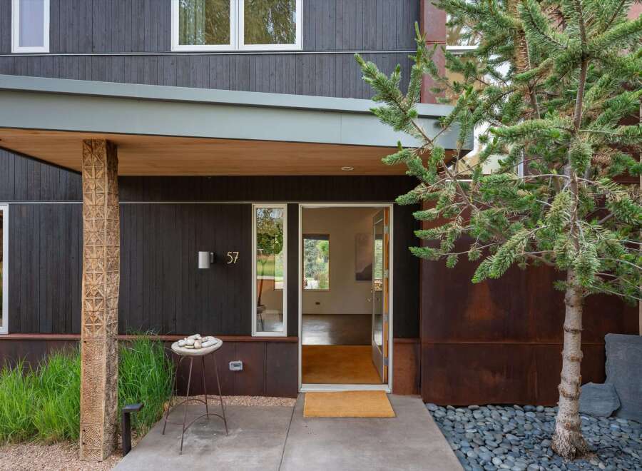 Discover modern living in this striking home featuring dark wood siding and a unique carved wooden pillar at the entrance.