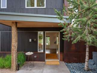 Discover modern living in this striking home featuring dark wood siding and a unique carved wooden pillar at the entrance.