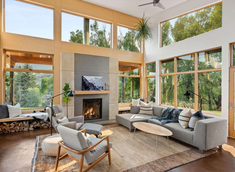 Experience modern living in this stunning great room, featuring a soaring ceiling and expansive windows that flood the space with natural light and offer breathtaking views of the surrounding nature.