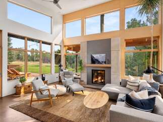 Experience modern living in this stunning great room, featuring soaring ceilings and expansive windows that flood the space with natural light and offer breathtaking views of the surrounding landscape.