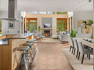 Experience modern living in this open-concept space, featuring a sleek kitchen island with bar stools and a stunning living area with a fireplace.
