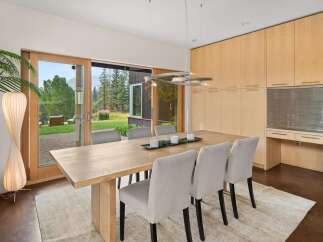 Experience seamless indoor-outdoor living in this elegant dining room, featuring a large wooden table and comfortable upholstered chairs.