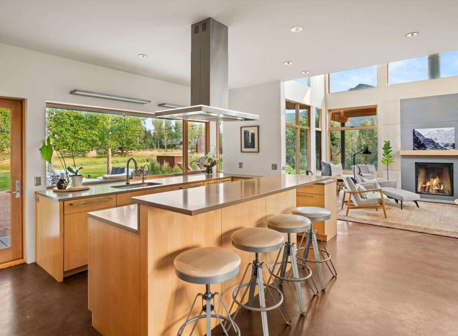 Experience modern living in this stunning open-concept kitchen and living area, featuring a large island with bar seating and a cozy fireplace.