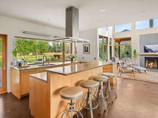Experience modern living in this stunning open-concept kitchen and living area, featuring a large island with bar seating and a cozy fireplace.