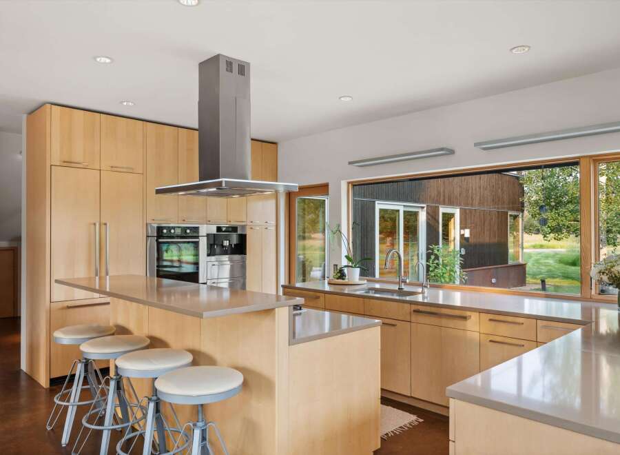 This modern kitchen boasts sleek, light wood cabinetry and a spacious island with comfortable seating.