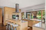 This modern kitchen boasts sleek, light wood cabinetry and a spacious island with comfortable seating.