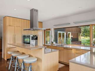 This modern kitchen boasts sleek, light wood cabinetry and a spacious island with comfortable seating.