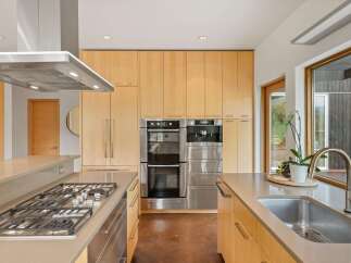 Experience modern luxury in this stunning kitchen, featuring sleek stainless steel appliances, including a double oven and built-in coffee maker.