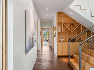 This modern hallway features a sleek design with a polished concrete floor and a striking staircase with stainless steel railings.