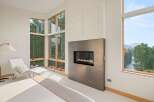 Experience modern luxury in this stunning bedroom featuring a sleek gas fireplace as a focal point.
