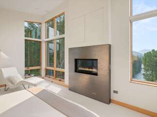 Experience modern luxury in this stunning bedroom featuring a sleek gas fireplace as a focal point.
