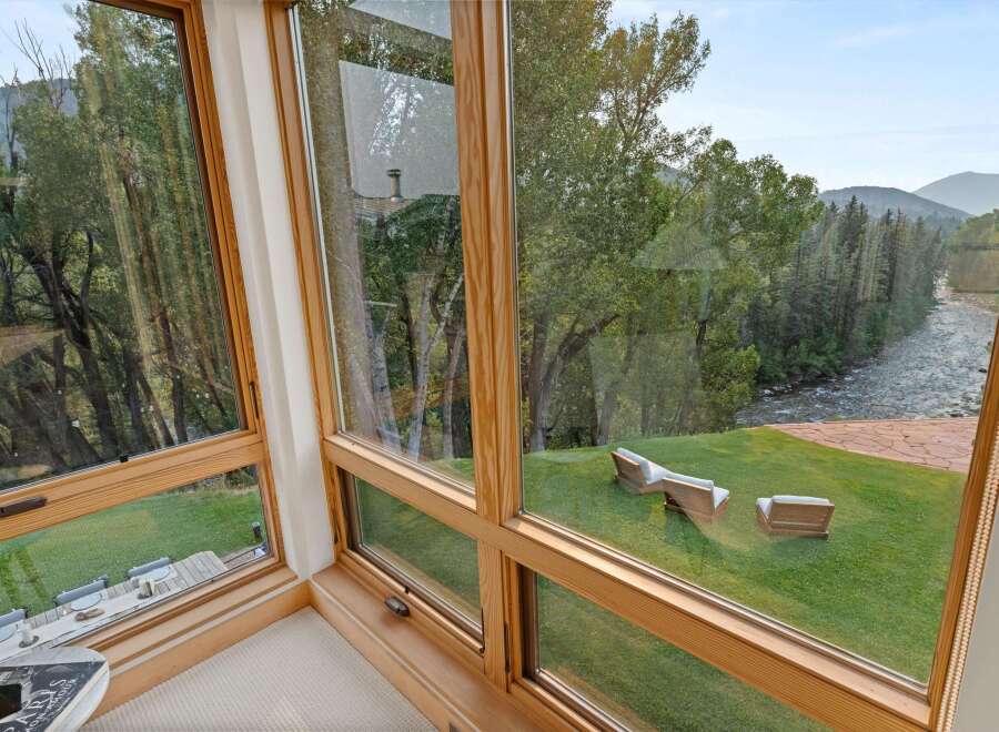Experience breathtaking views from this stunning home, featuring expansive windows that frame a serene river and lush forest.